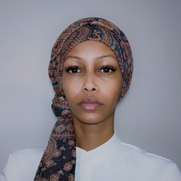Photo portrait of Faduma Ahmed against a white wall wearing a head scarf.