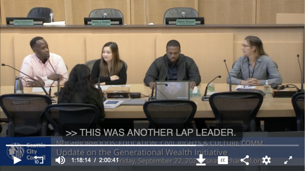 Screenshot of a video recording. Four people, including two PEL Lab Leaders, sit at a table in Seattle City Council Chambers to present to the City Council.